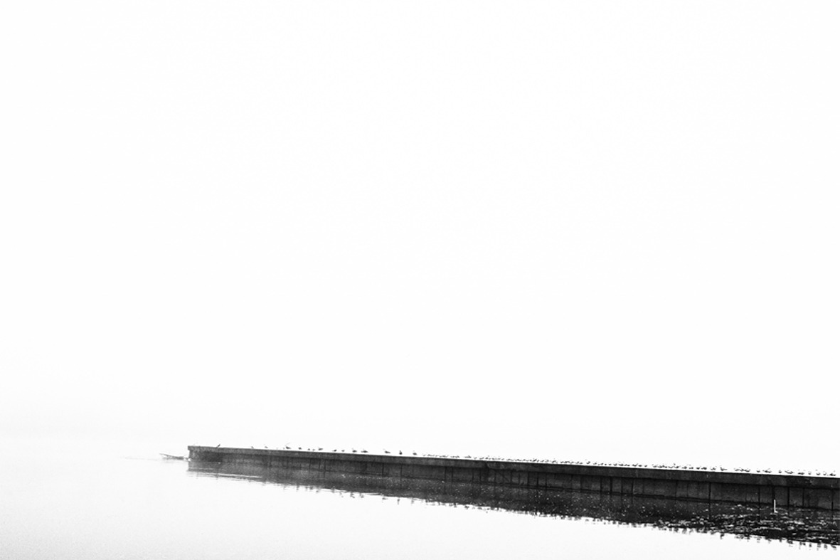 A narrow embankment extending into white fog