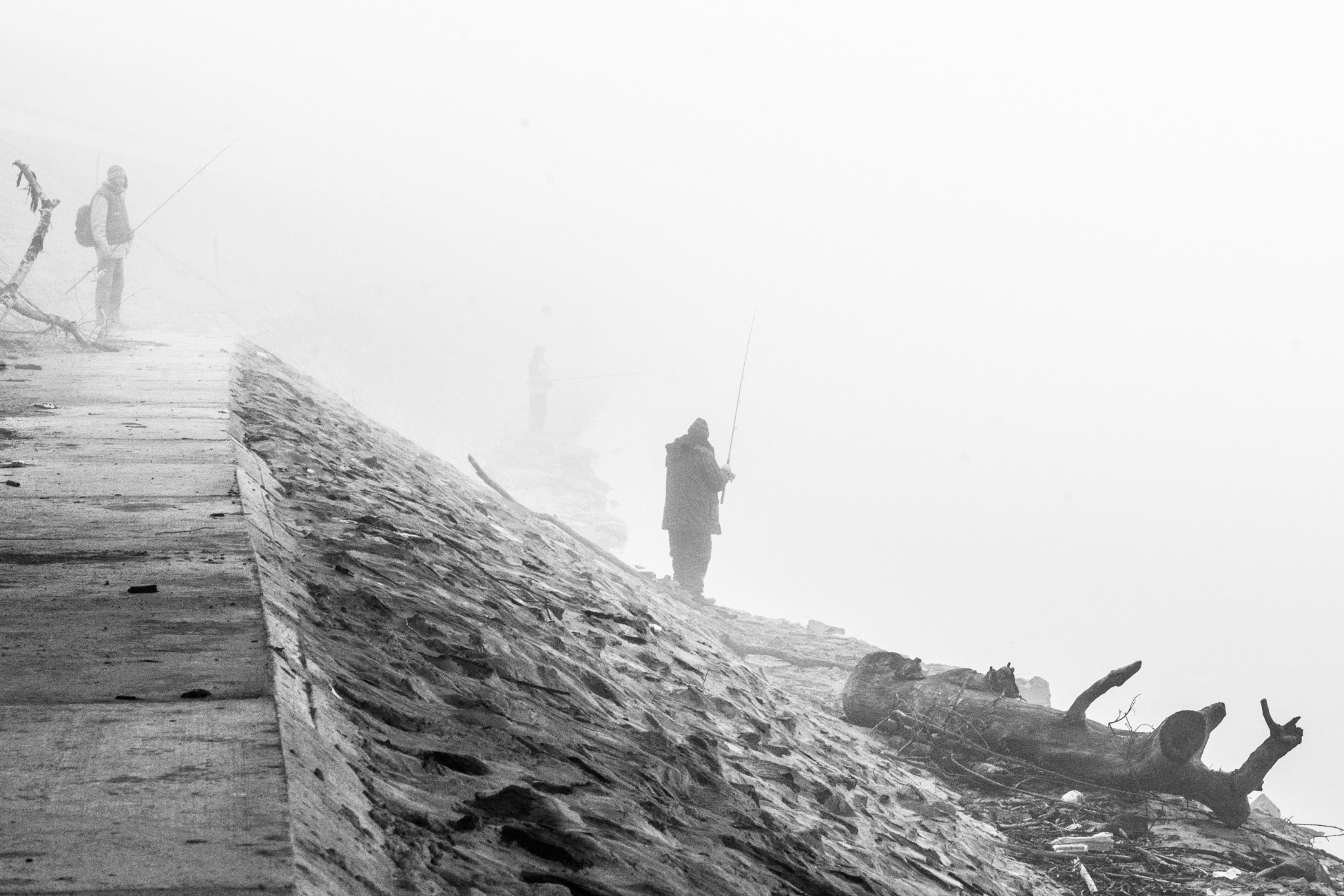 A lone fisherman standing beside the river in fog