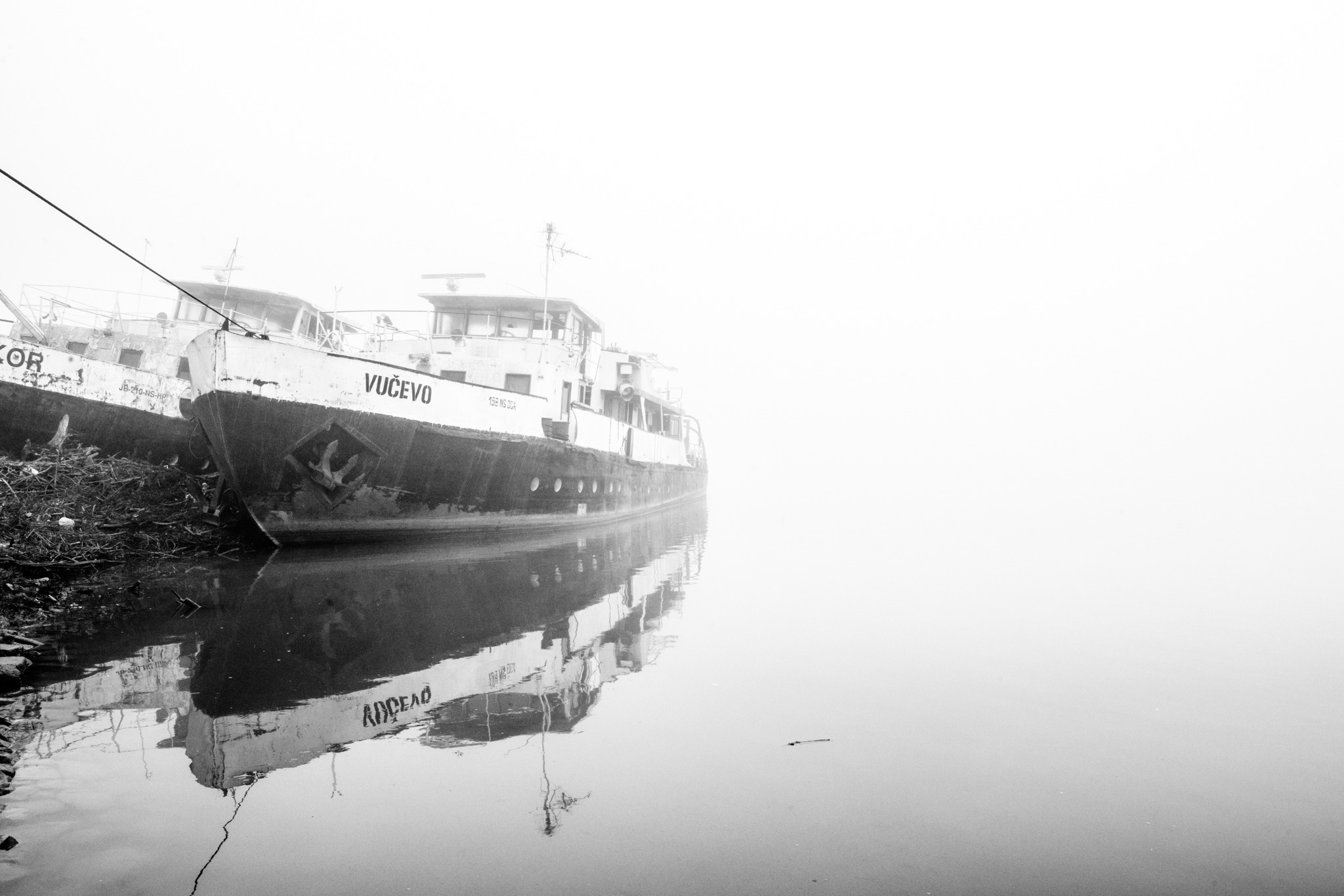 A moored ship reflected in still river water