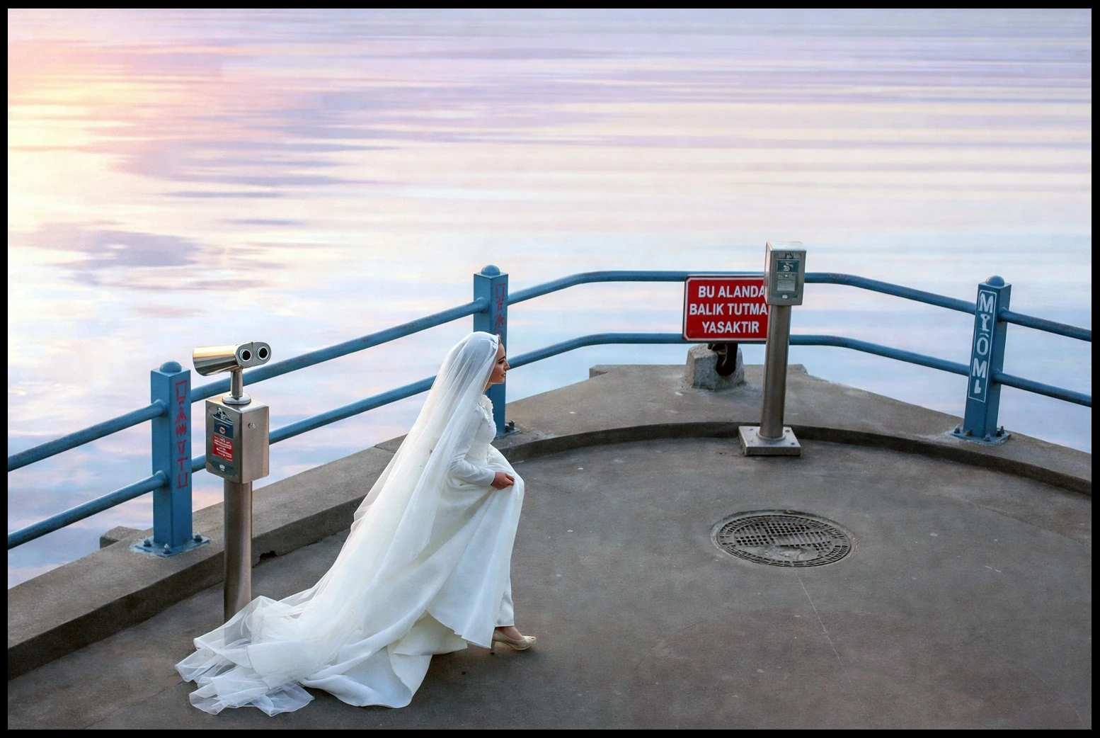 A bride moving beside blue railings overlooking the water