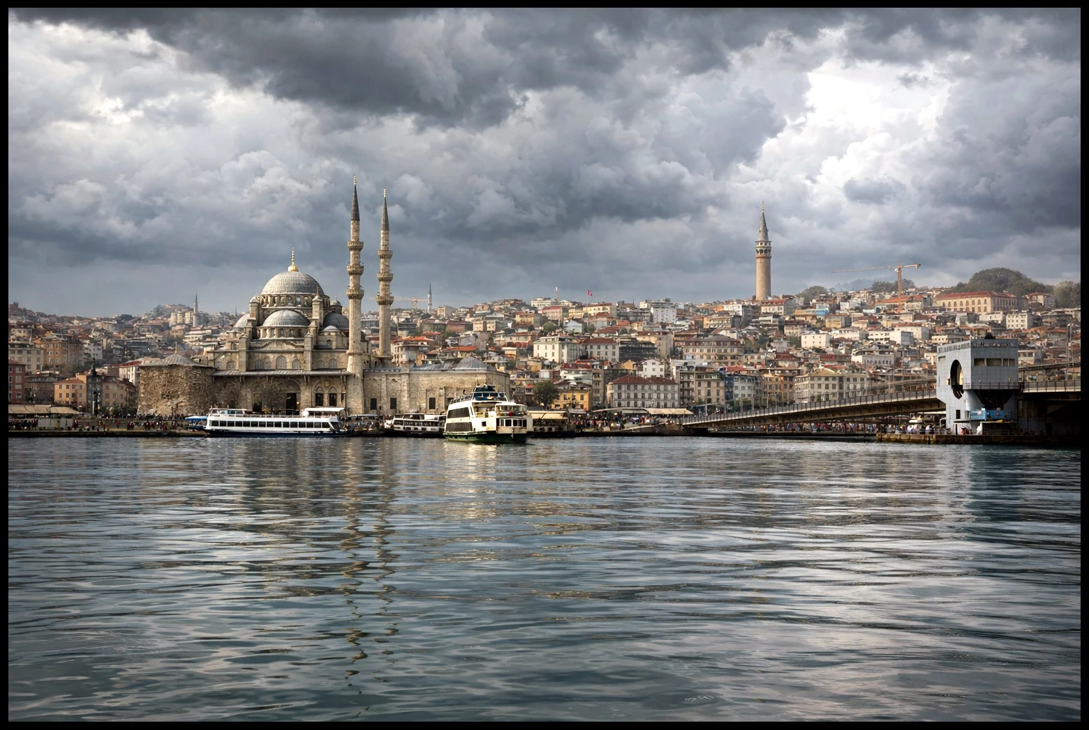 A mosque and bridge along a densely built waterfront under clouds