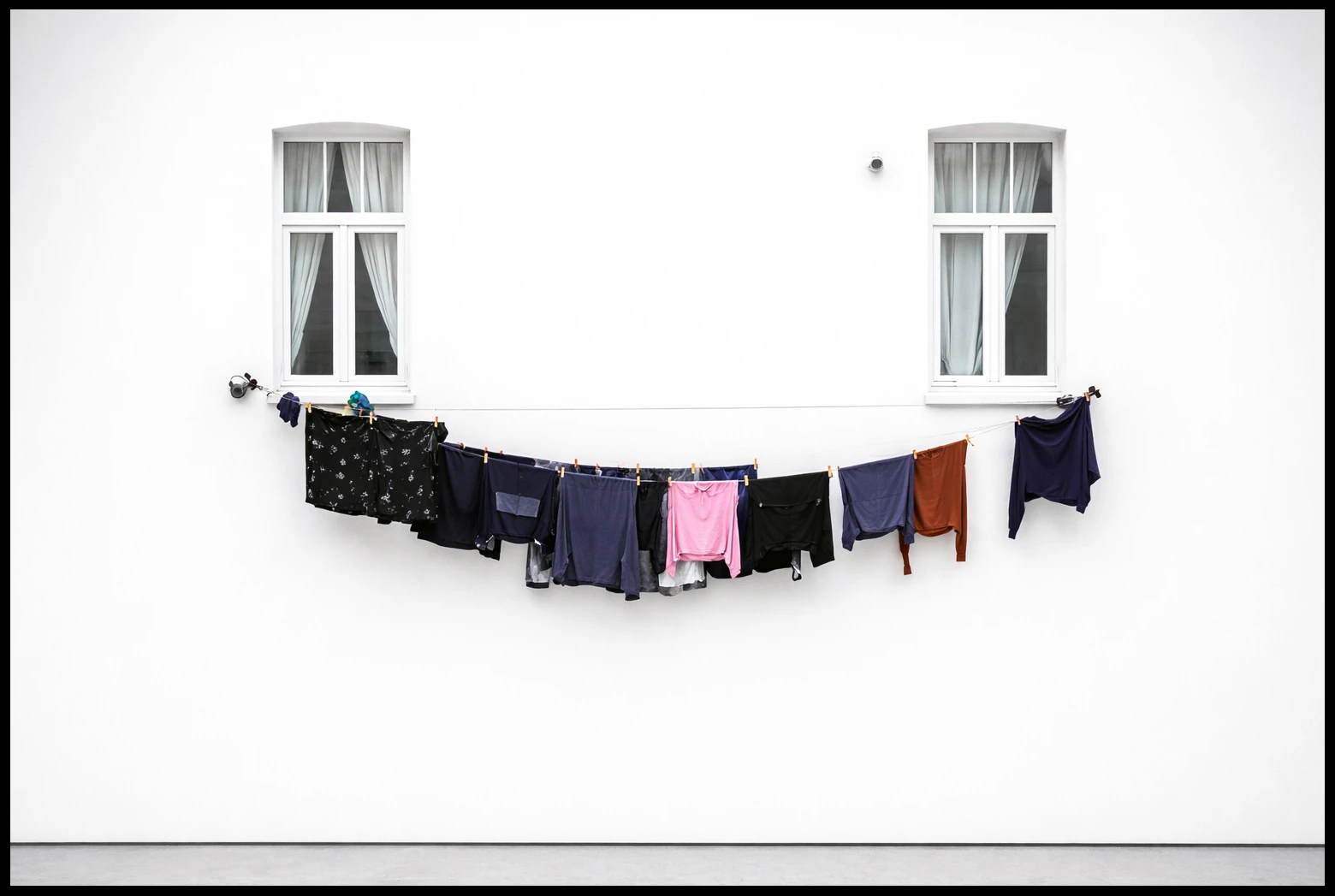 A clothesline strung between two windows on a white facade