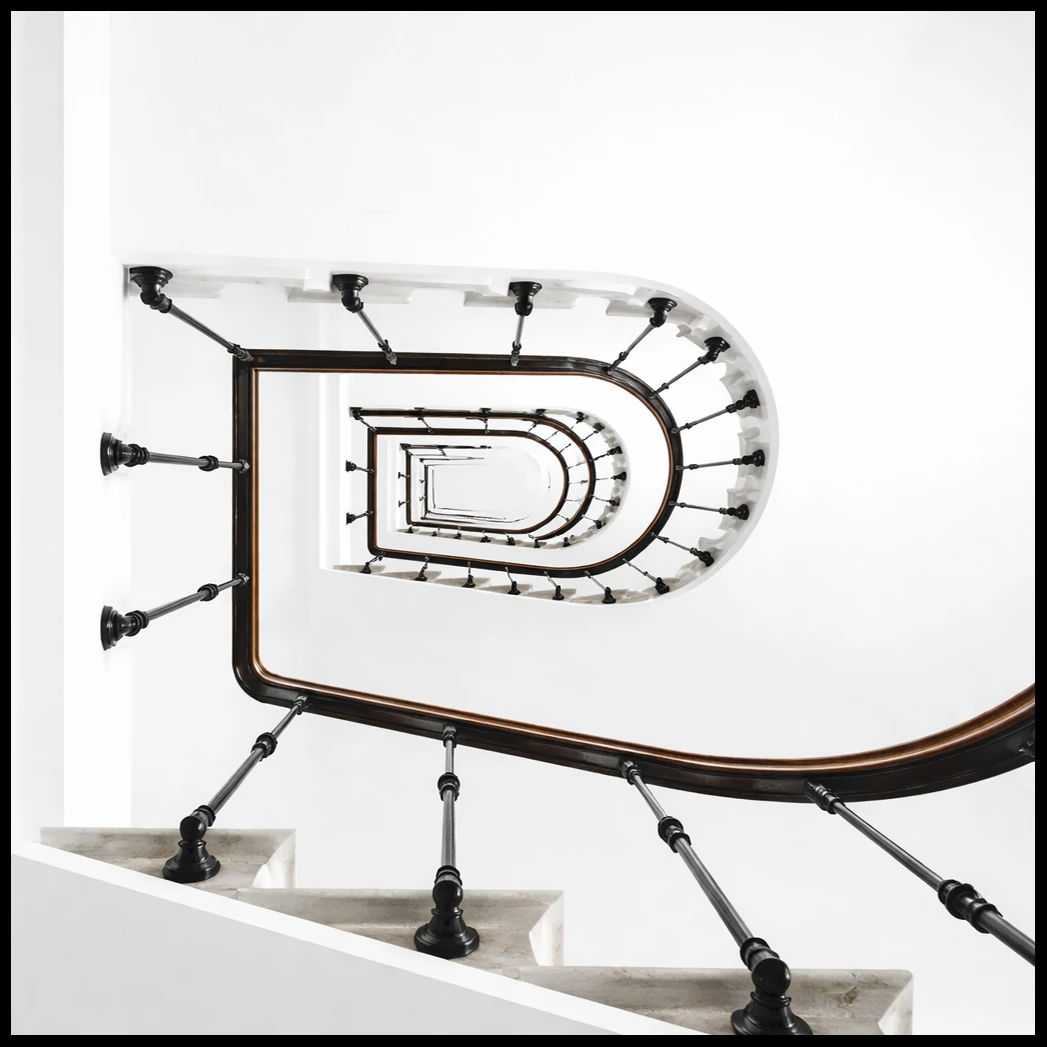 A curved staircase with dark railings seen from below