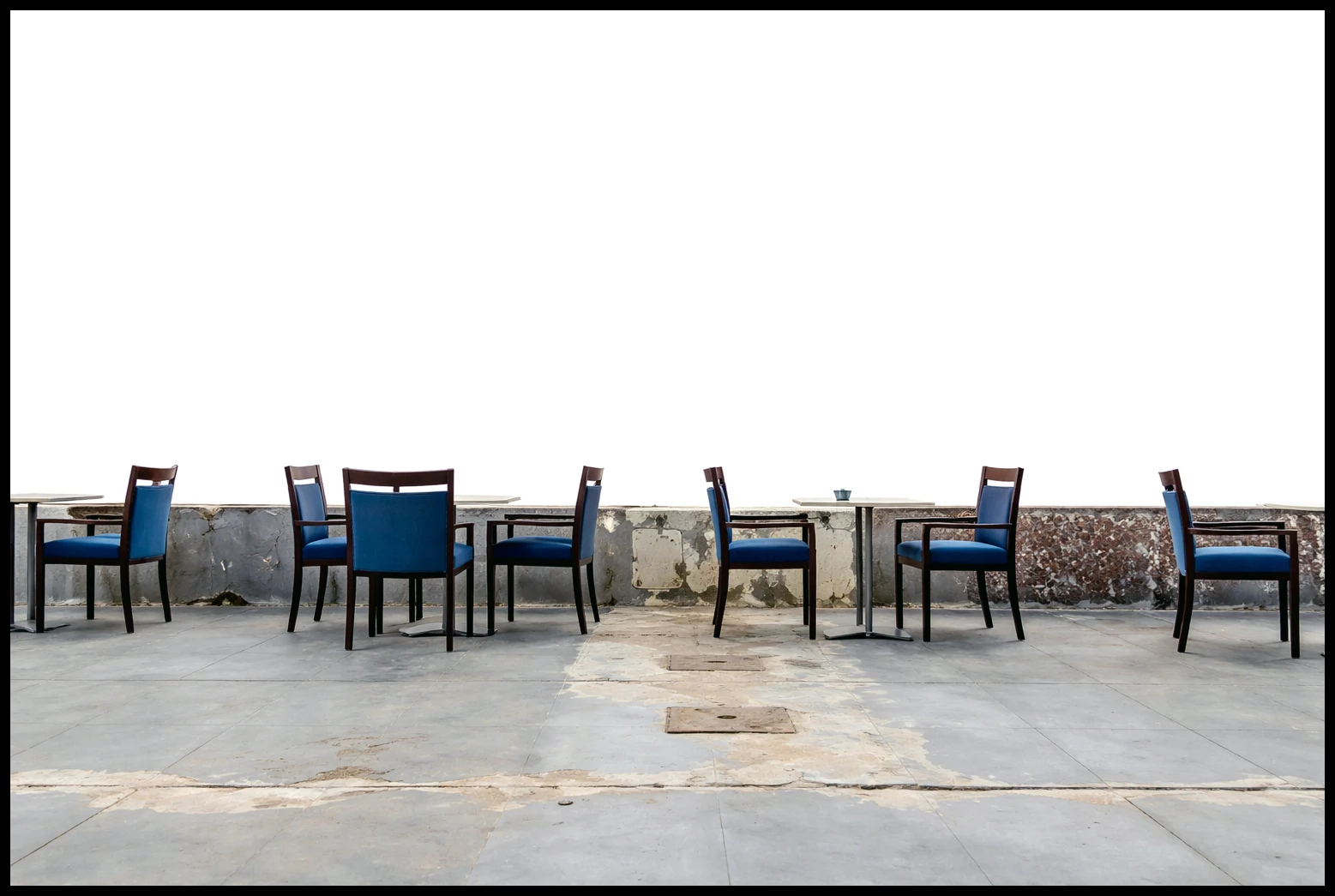 Empty blue chairs and small tables facing the water