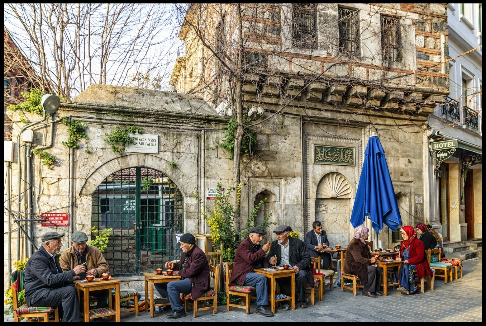 People drinking tea at small tables beside a weathered building