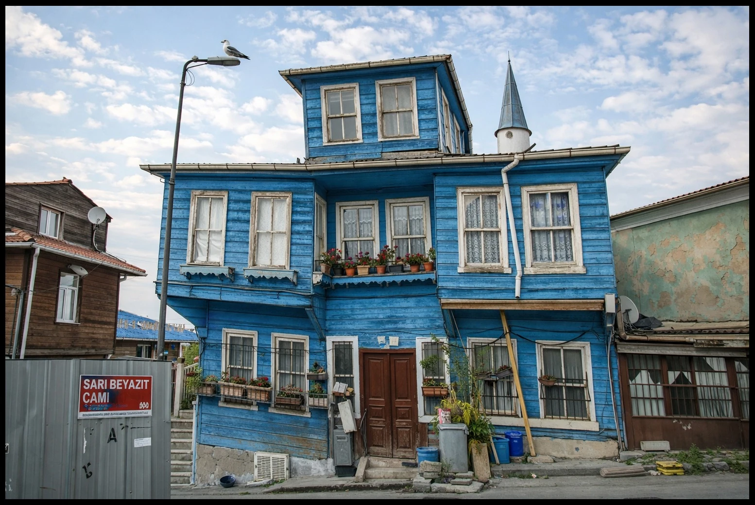 A blue wooden house with white trim beside other buildings