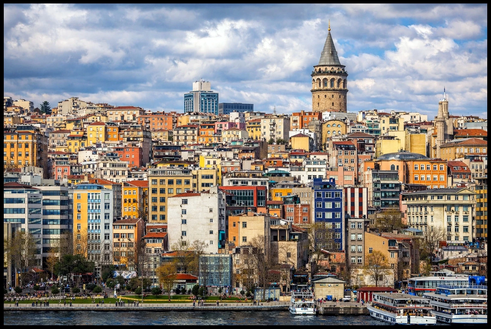 Colourful buildings rising towards Galata Tower beneath a blue and cloudy sky