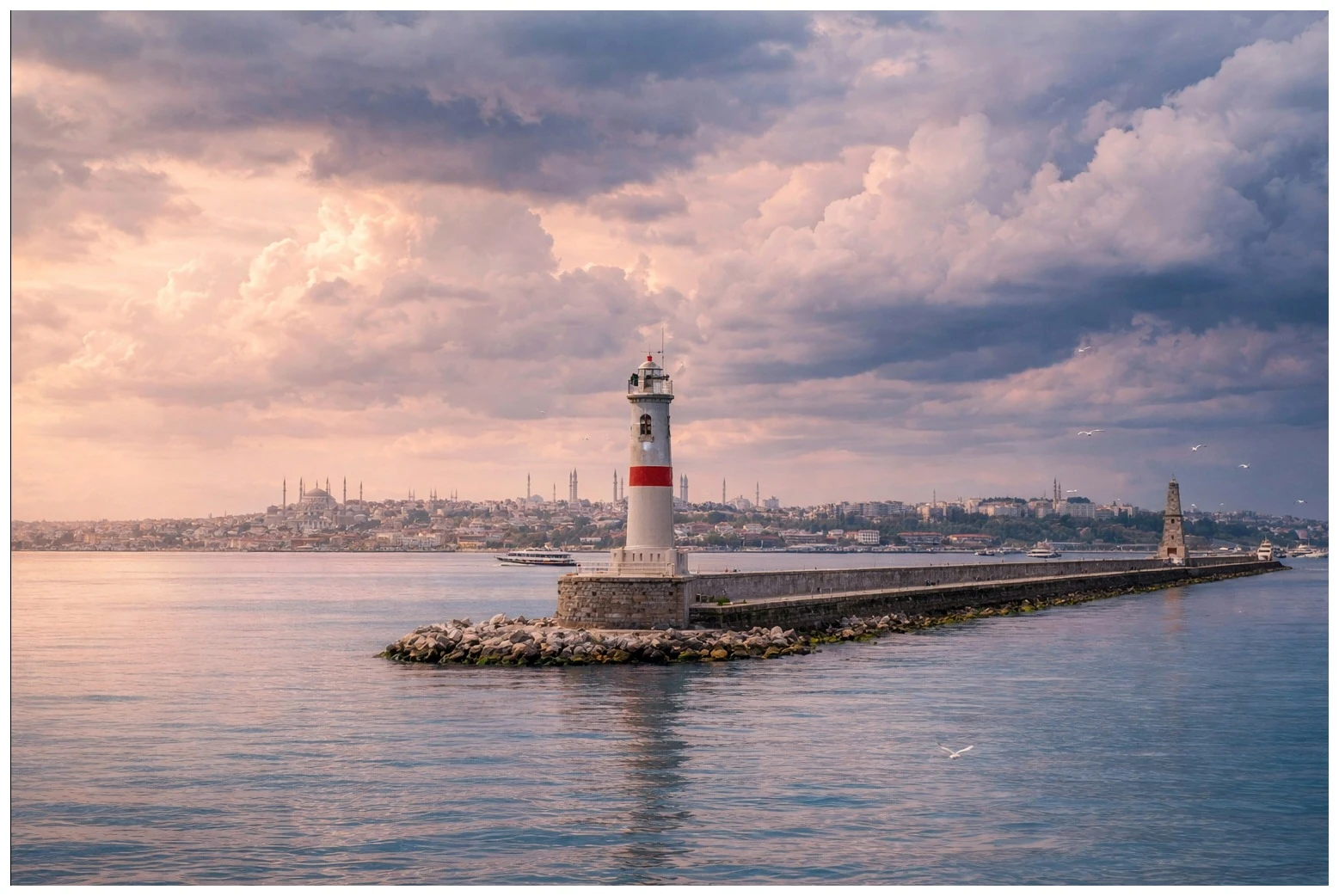 A lighthouse on a breakwater beneath a pastel evening sky