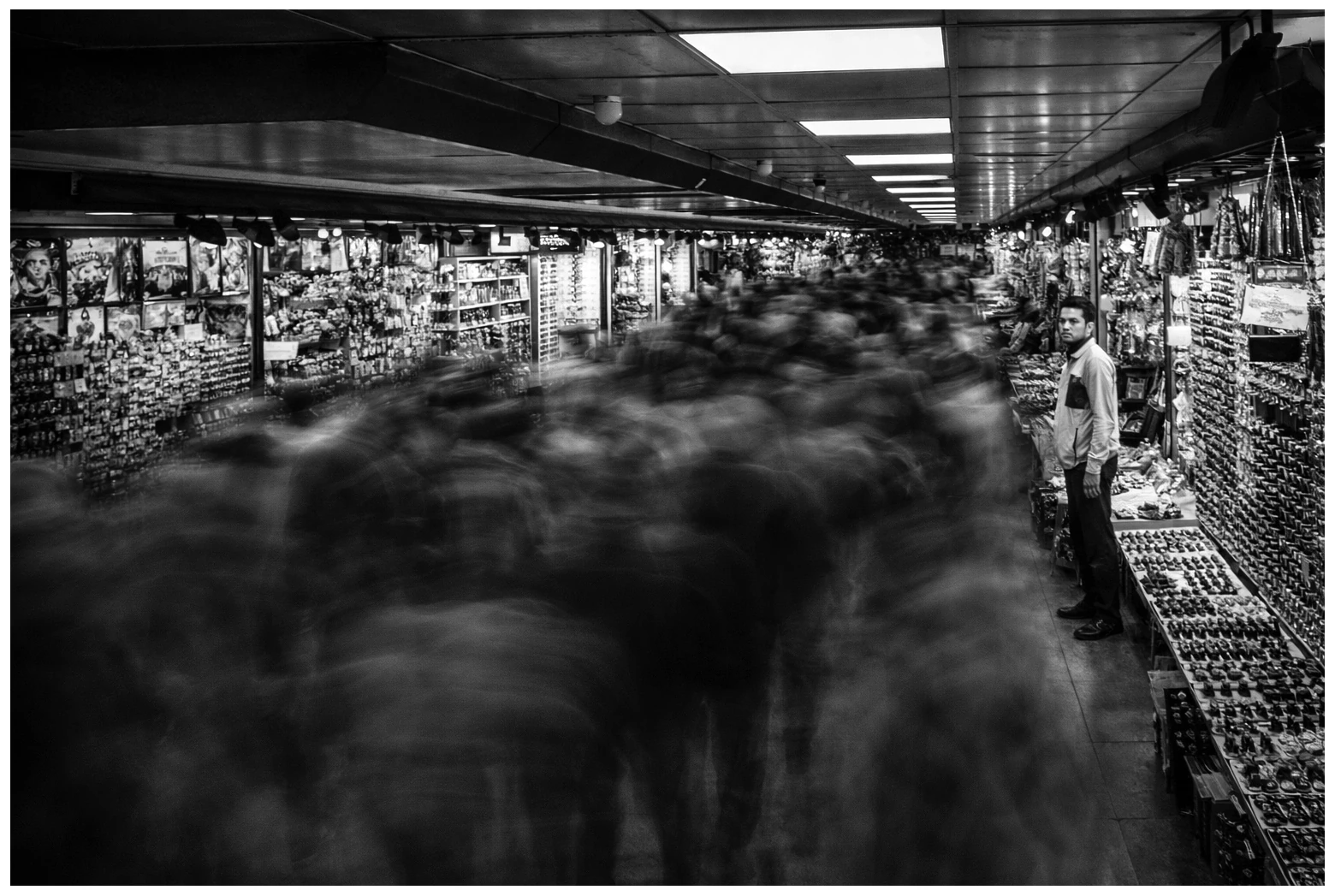 A monochrome long-exposure scene of people passing through a covered market