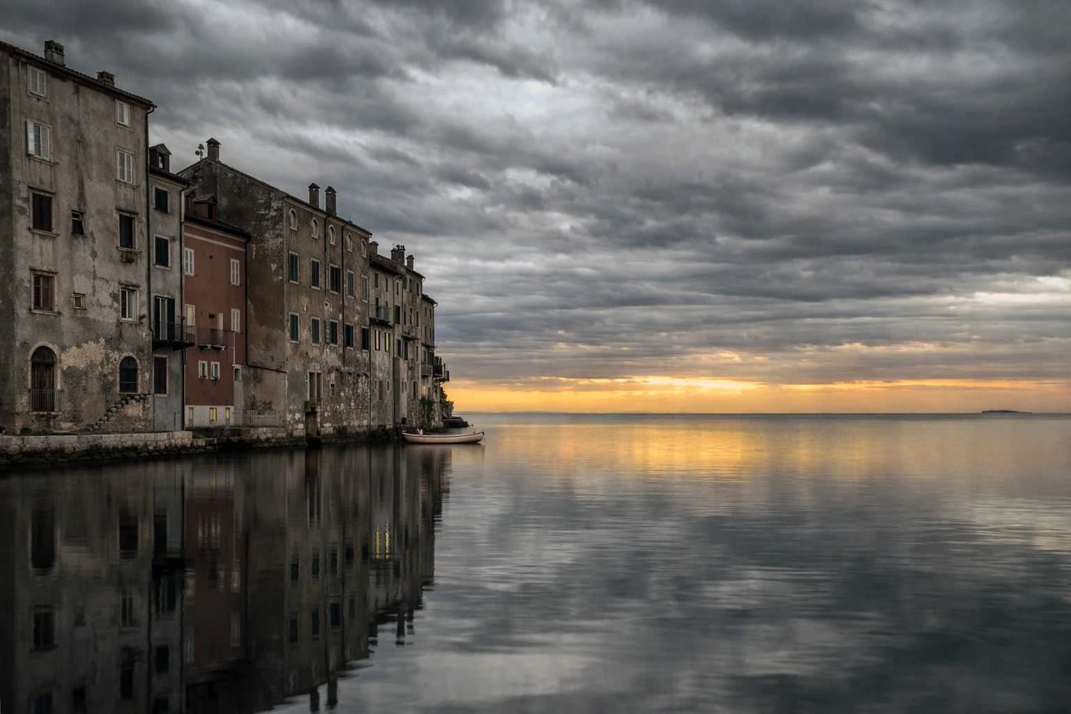 Waterfront buildings reflected in still water beneath a sunset sky