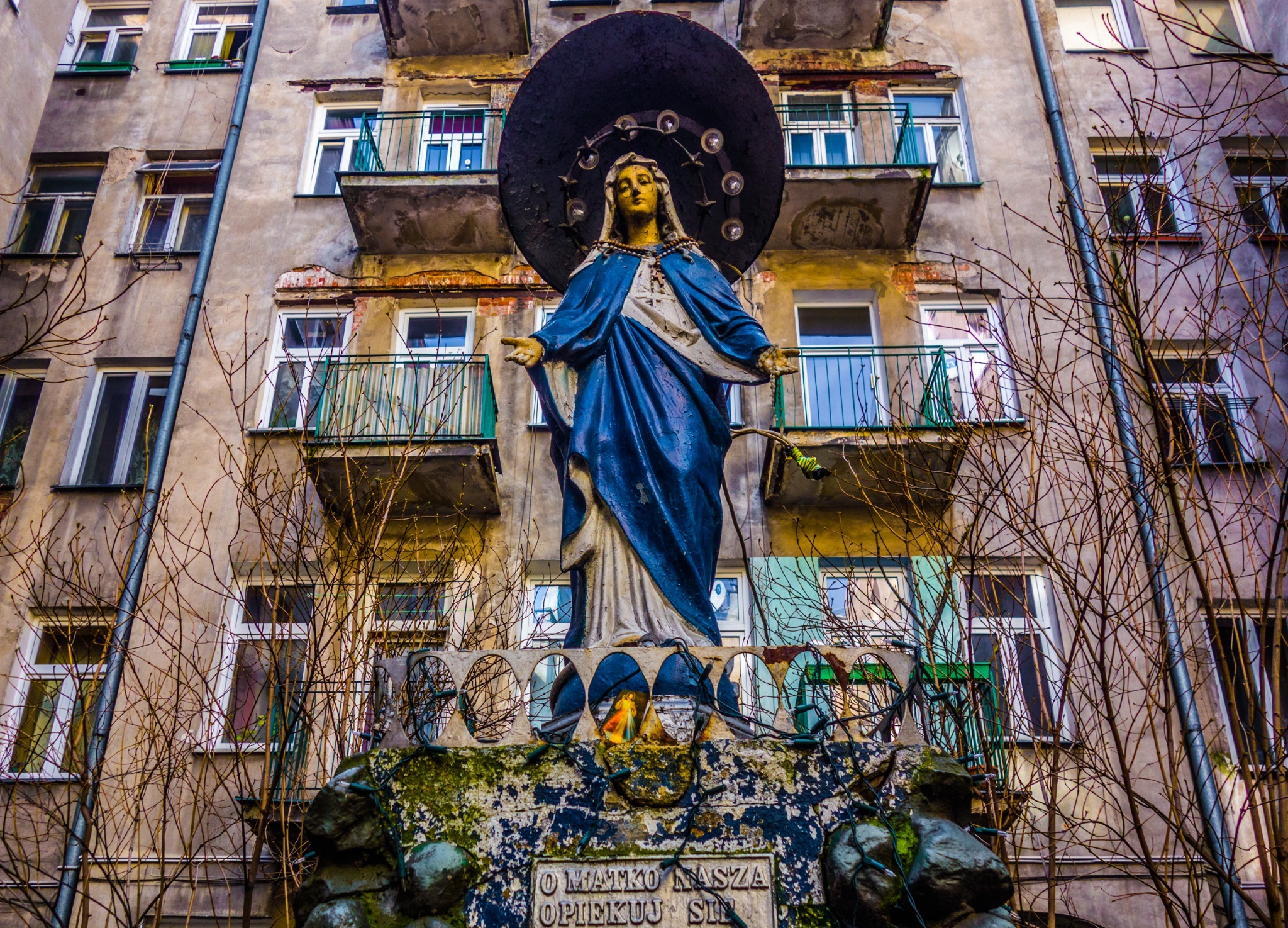 A statue of Mary in blue beneath apartment balconies